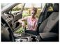 Vrouw stofzuigt auto-interieur met een handstofzuiger.