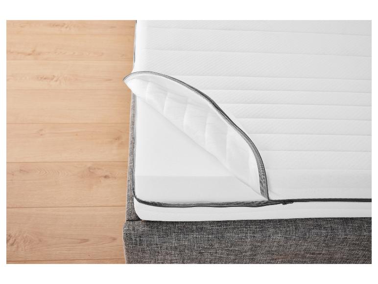 Wit matras met ritssluiting op een grijze bedbodem.