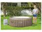 Vrouw vult een opblaasbare jacuzzi met water op een gazon.