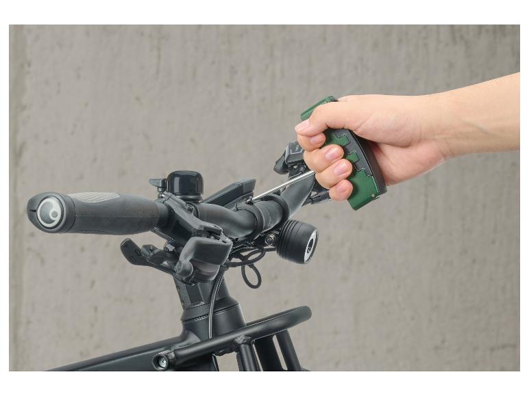 Hand houdt groen gereedschap vast op een fietsstuur met accessoires.