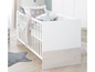 Witte babybed met sterrenprint en houten basis.