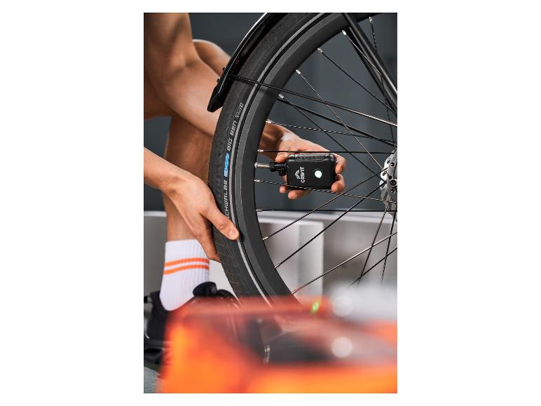 Persoon pompt een fietsband op met een draagbare luchtpomp.