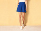 Een vrouw draagt ​​blauwe shorts en witte sneakers.