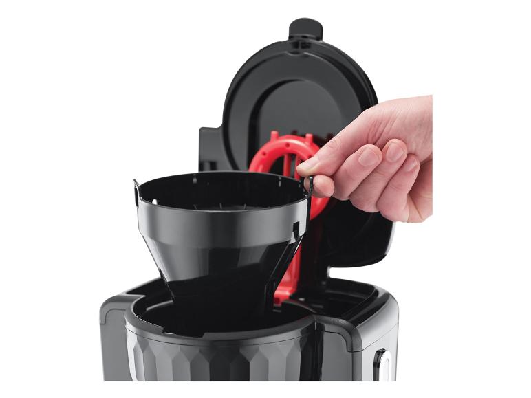 Hand plaatst zwart koffiefilter in koffiezetapparaat.