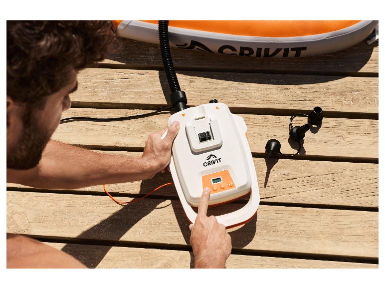 Man pompt een CRIVIT SUP-board op met een 20 V pomp op een houten vlonder.