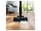 Draadloze steelstofzuiger reinigt houten vloer, met de tekst 'POWER BRUSH'.
