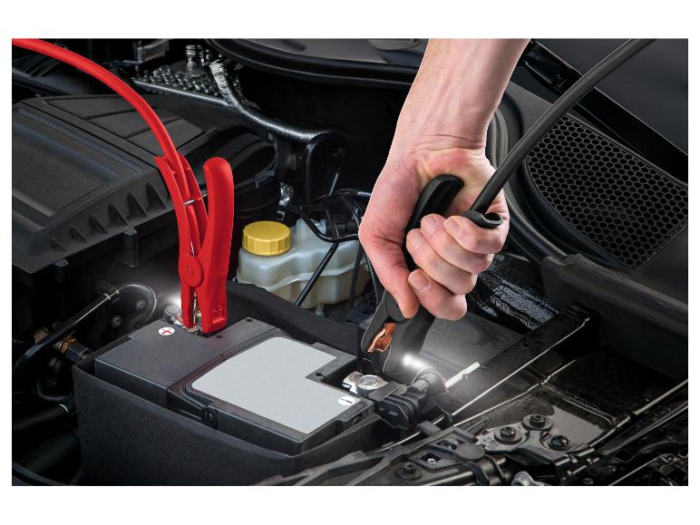 Hand bevestigt startkabel aan autoaccu.