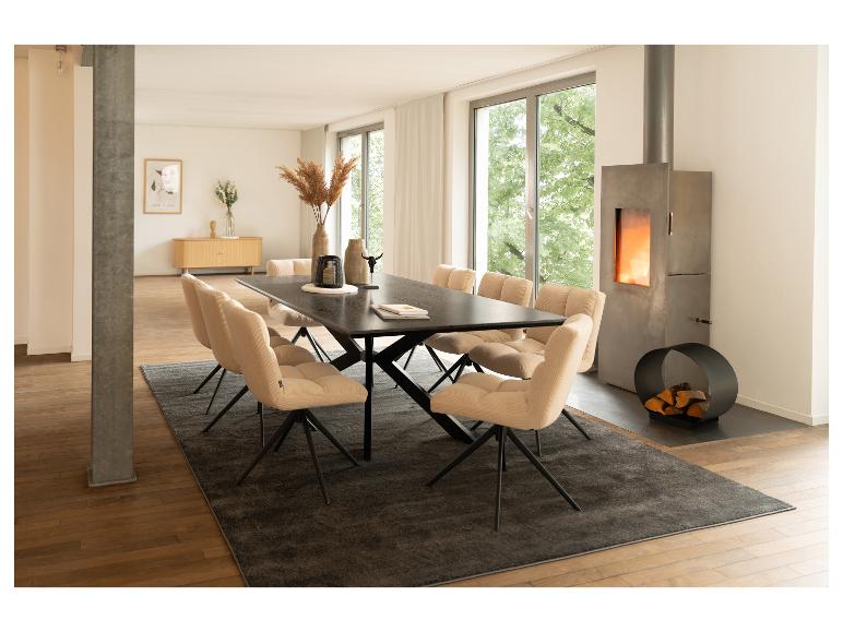Moderne eetkamer met zwarte eettafel, beige stoelen en betonnen open haard.