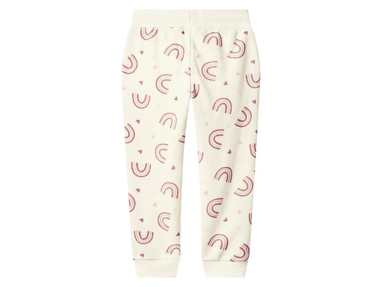 Crèmekleurige kinderjoggingbroek met roze regenboog- en hartpatronen.