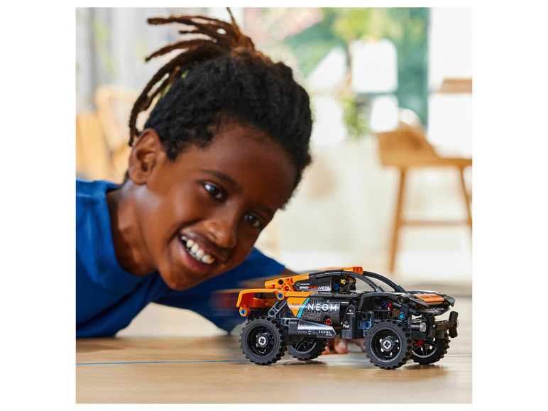 Een kind speelt met een LEGO Technic off-road voertuig.