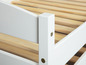 Detail van een wit houten bedframe met lattenbodem.