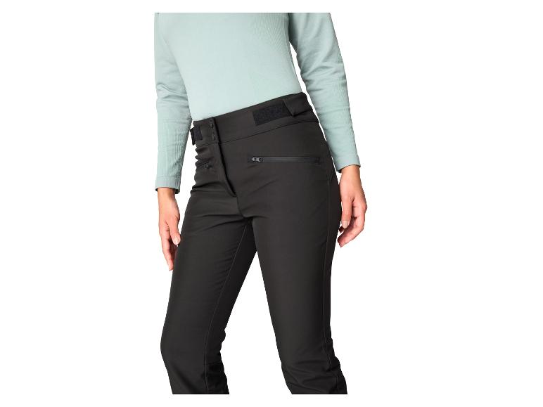 Zwarte outdoorbroek met ritsen en een lichtgroen shirt met lange mouwen.
