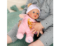 Een kind houdt een babypop vast in een roze kruippakje en een wit mutsje.