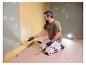 Man schildert muur, verlicht door LIVARNO® werklamp 'The Painter+'.
