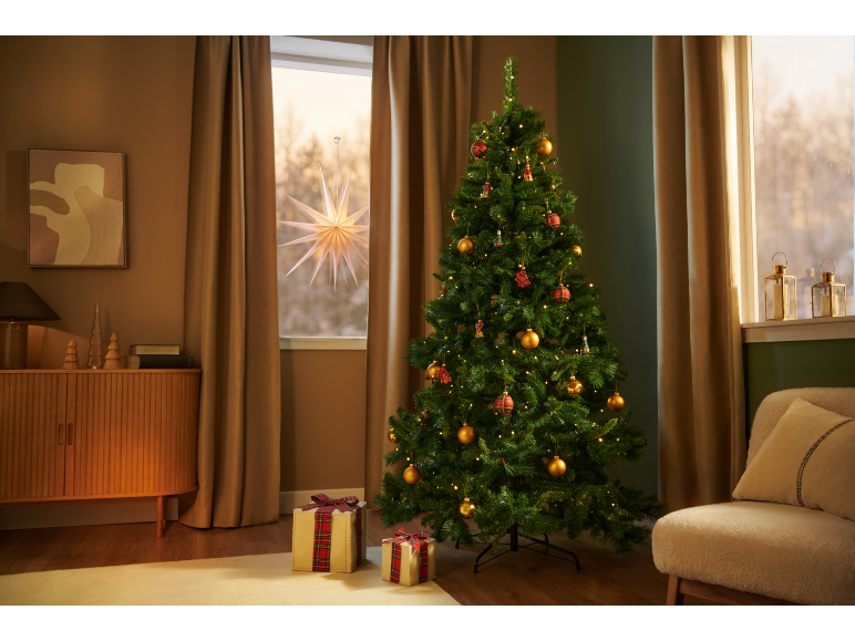 Kerstboom met lichtjes en versieringen, cadeaus, een lichtgevende ster in het raam.