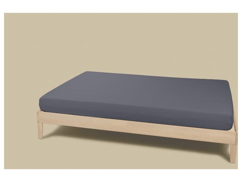 Licht houten bed met een donkergrijs hoeslaken.