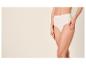 Vrouw in beige slip met hoge taille, met hand op dij.