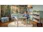Kinderkamer met een huisvormig bed, een kleine tafel en stoelen, en boekenopslag.