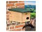 Houten vogelhuisje aan bakstenen muur met vliegende zwaluw.