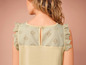Een beige top met delicate broderie anglaise details.