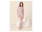 Vrouw in lichtroze tweedelige pyjama, bestaande uit een lange broek en een top met lange mouwen en knoopjes.