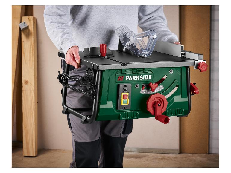 Persoon draagt een groene tafelzaag met een rode slinger en bedieningselementen, klaar voor houtbewerking.