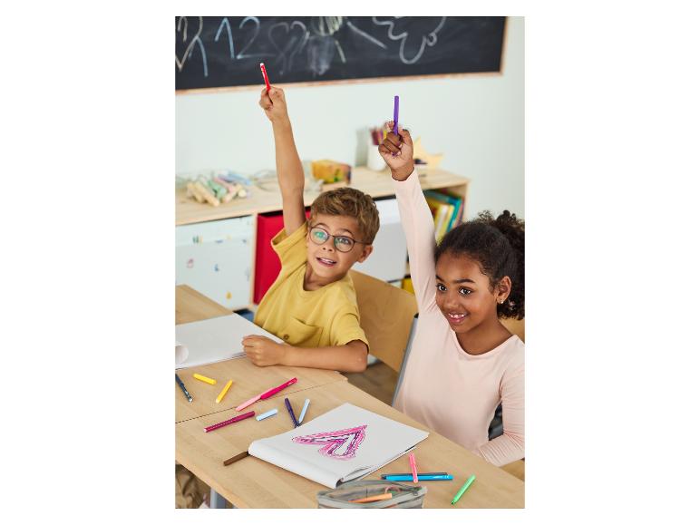 Twee kinderen in een klaslokaal met viltstiften en tekeningen, die hun handen opsteken.