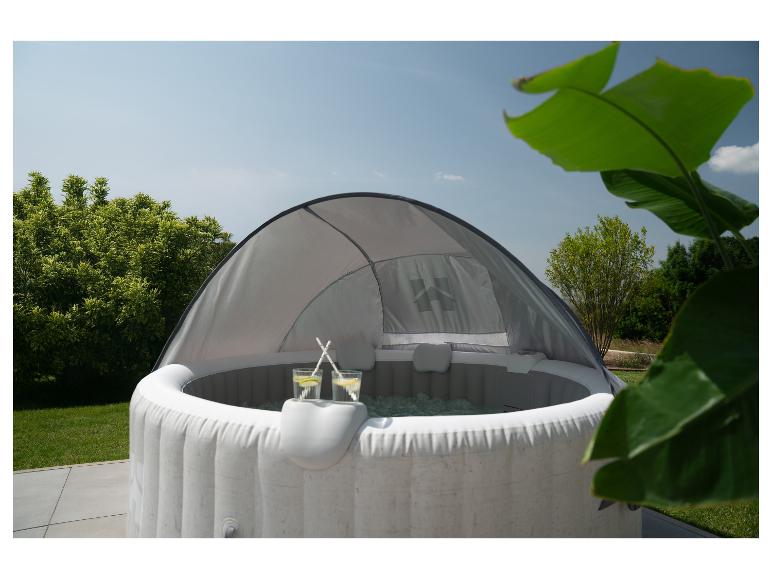 Opblaasbare jacuzzi met overkapping, twee drankjes en groene tuinachtergrond.