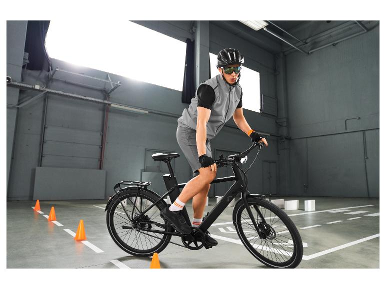 Man in reflecterend vest en fietsbril op een fiets, oefenend tussen pionnen.