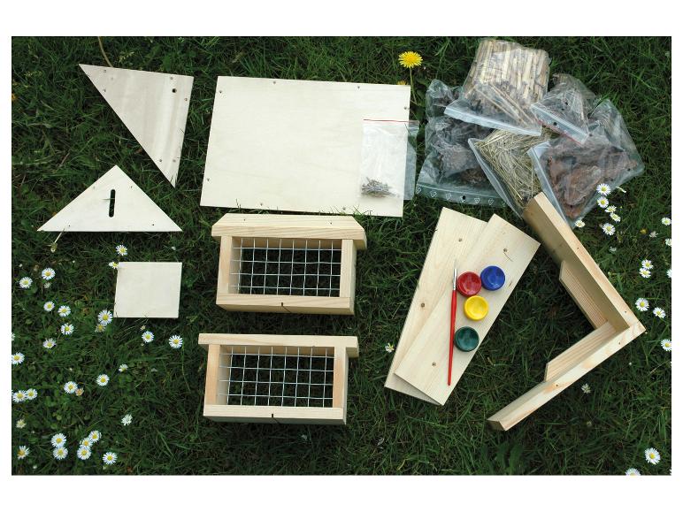 Houten insectenhotel bouwkit met verf en vulmaterialen op gras.