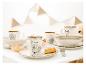 Kinderservies met dierenmotieven en alfabet, inclusief mokken, borden en kommen, op een witte tafel.