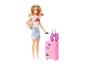 Pop met blond haar, zonnebril, roze koptelefoon, wit t-shirt, blauwe rok en roze koffer.