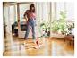Een vrouw mopt met een Vileda-mop op een houten vloer.