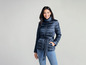 Een vrouw draagt een donkerblauwe gewatteerde jas met een riem.