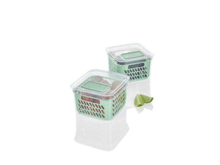 Twee groene opbergbakken met deksels en fruit