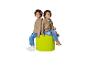 Twee kinderen zitten rug aan rug op een groene poef, gekleed in hoodies en jeans.