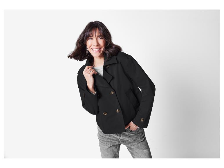 Lachende vrouw in een zwart dubbelknoops jasje.