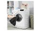 Persoon stopt zwarte was in een wasmachine in een wasruimte.