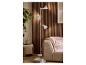 Witte vloerlamp met drie verstelbare spots naast een beige bank en houten wandpanelen.