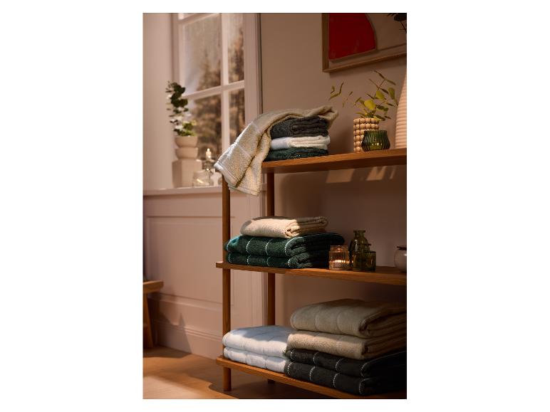 Gevouwen handdoeken op een houten plank, met decoraties en een raam op de achtergrond.