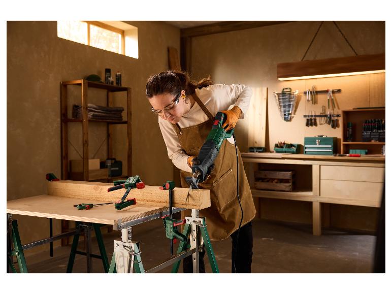 Vrouw in een werkplaats zaagt een houten balk met de PARKSIDE PFS 850 C3 reciproke zaag.