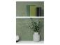 Groene boeken en een vaas met eucalyptus op witte planken tegen een groene muur.