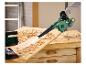 Groene accublazer die houtsnippers van een houten werkbank blaast.
