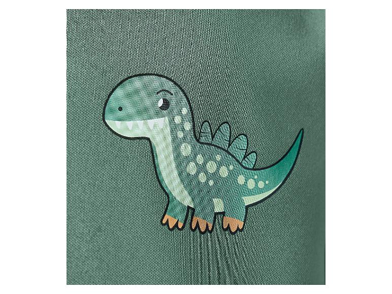 Close-up van een schattige groene cartoon dinosaurus met witte stippen op een groene stof.