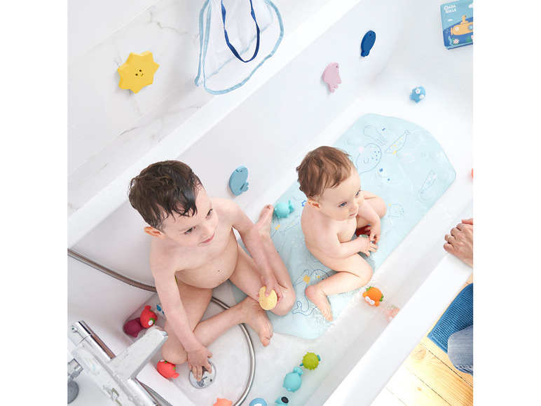 Twee kinderen in bad met badspeelgoed en een badmat met zeedierenmotief.