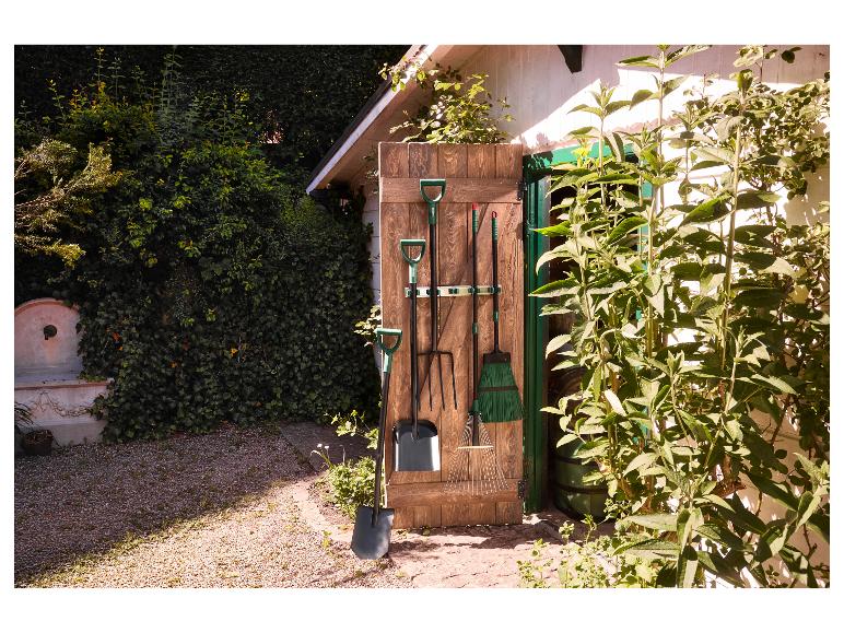 Tuin gereedschap hangend aan een houten muur buiten een tuinhuisje.