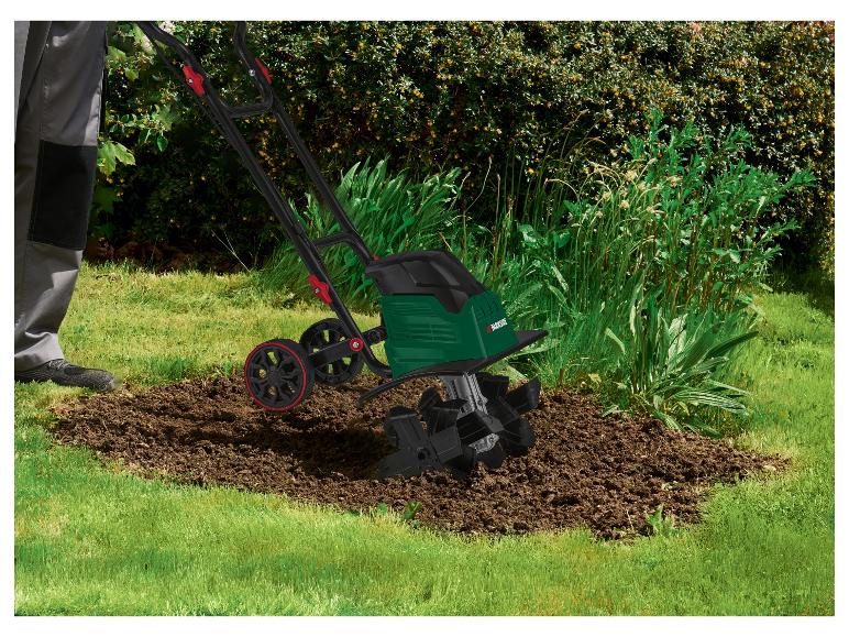 Persoon gebruikt een Parkside elektrische tuinfrees om grond te bewerken in een tuinbed.