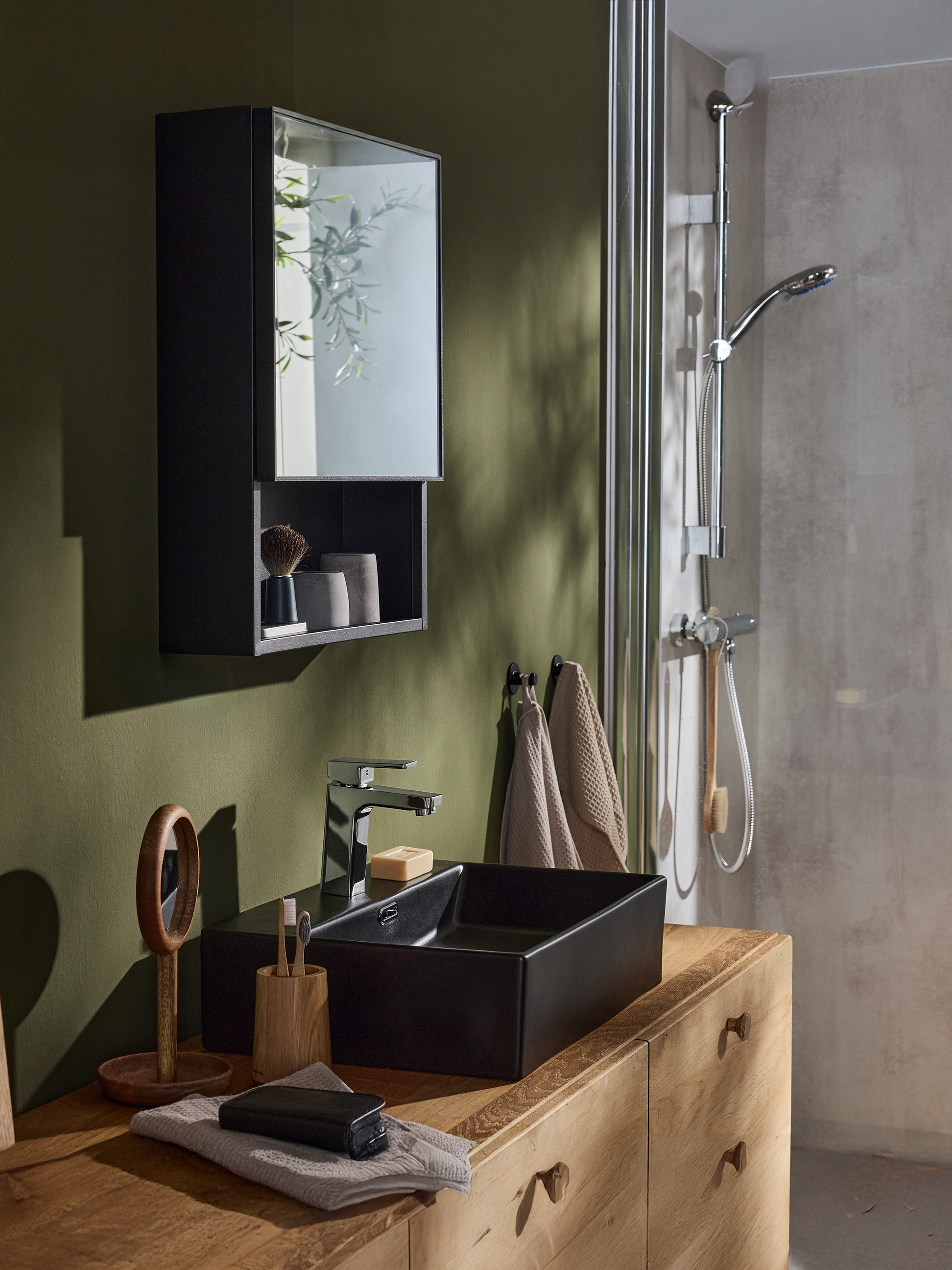 Een moderne badkamer met een zwarte kast, zwarte wastafel, chromen kraan en een douche.