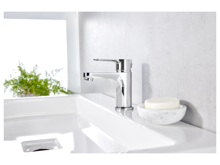 Moderne badkamerkraan en marmeren zeepbakje op een wit wastafel.