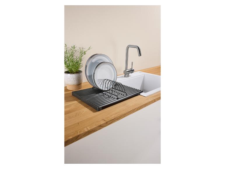 Afwasrek met borden naast een gootsteen en een potplant.